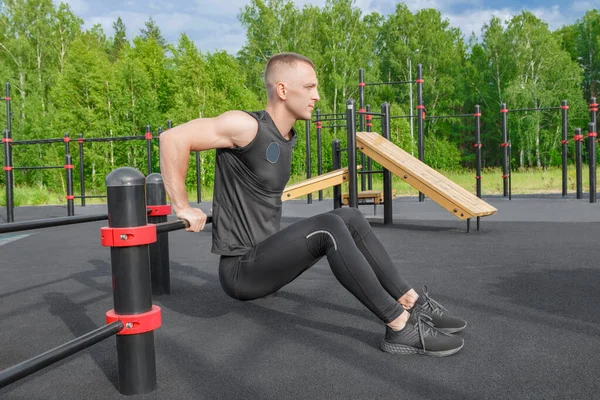 Jeune homme en forme faisant des exercices de trempettes triceps pendant l'entraînement croisé en plein air. — Photo