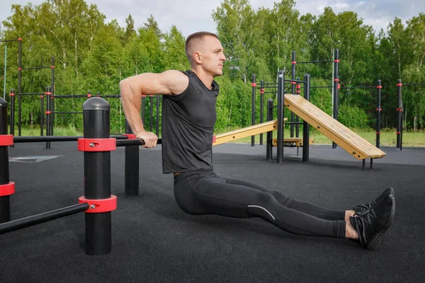 Jeune homme en forme faisant des exercices de trempettes triceps pendant l'entraînement croisé en plein air. — Photo