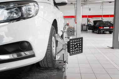 Araba tekerleklerinin elektronik ayarı. Lastik, garajda hizalanan otomatik tekerlek hizasına kenetlendi. Arabanın elektronik ayarı. Modern atölyede profesyonel araba bakımı..