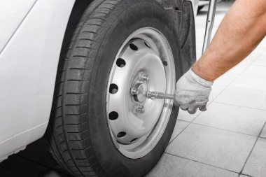 Tamirci yeni bir lastik takıyor. Tamirci modern bir arabanın direksiyonunu değiştiriyor tamirci de oto tamirhanesinde tekerlek değiştiriyor..