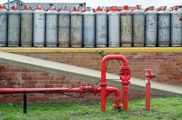 Tuyau d'eau de la bouche d'incendie devant les bouteilles de gaz lpg — Photo
