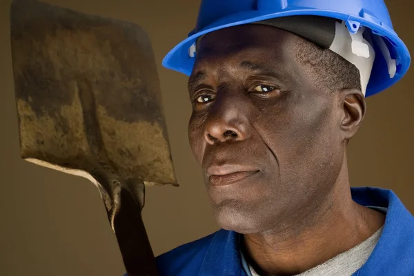 Stavební dělník odpočívá lopatu na rameni — Stock fotografie