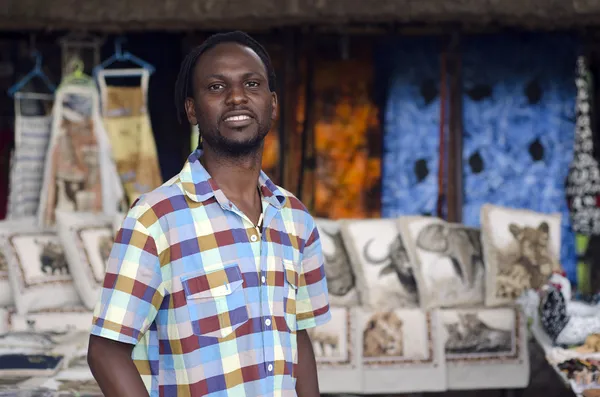 Vendedor de curio africano frente a artículos de vida silvestre étnicos — Foto de Stock