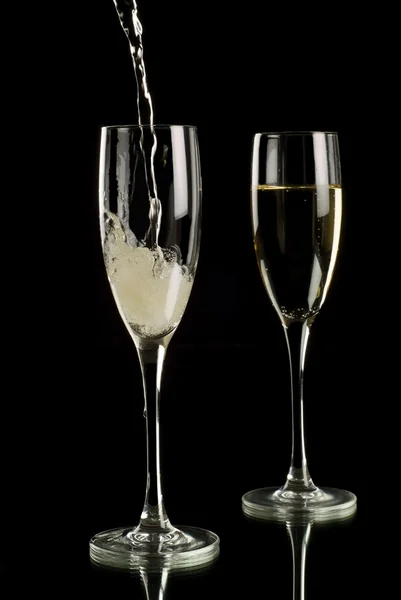 Vino espumoso vertido en flautas de champán — Foto de Stock