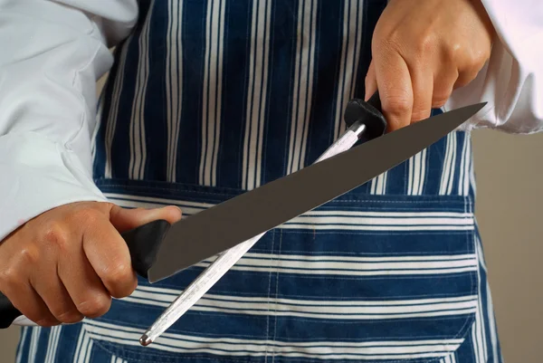 Woman chef sharpening knif — Stockfoto