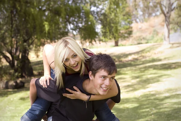 Piggyback chica en la espalda en el parque con hierba — Foto de Stock