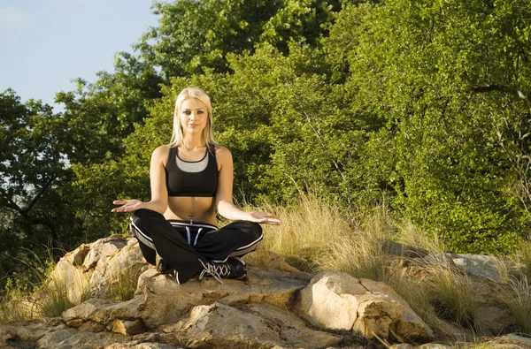 Vrouw mediteren open hand yoga op rots — Stockfoto