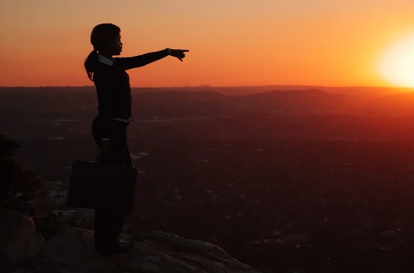 Silhueta de mulher de negócios no topo da colina durante o pôr do sol — Fotografia de Stock