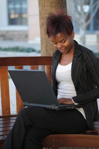 Affärskvinna på bänk med laptop — Stockfoto