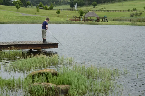 Boy bass fishing on dam or lake pier — Stock Photo, Image