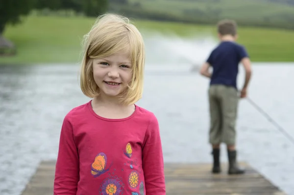 Young girl and boy fishing on wooden pier — Stock Photo, Image