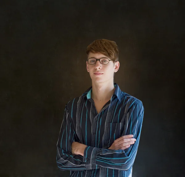 Young business man against a dark blackboard background — Stock Photo, Image