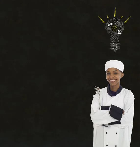 Engrenagem cog lightbulb ideia Africano mulher chef no giz blackboard fundo — Fotografia de Stock