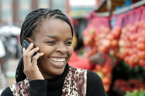 Afrikaanse of zwarte Amerikaanse vrouw bellen op mobiele GSM telefoon in township Stockfoto