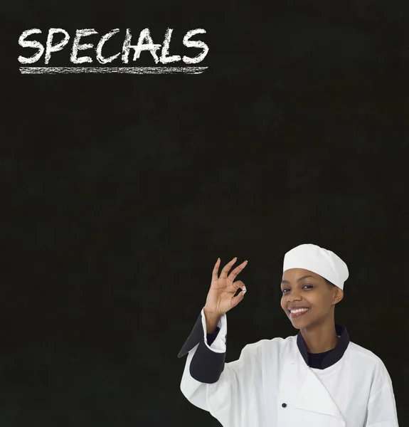 Afro-américaine femme chef avec craie spéciale signe sur tableau noir Arrière-plan — Photo