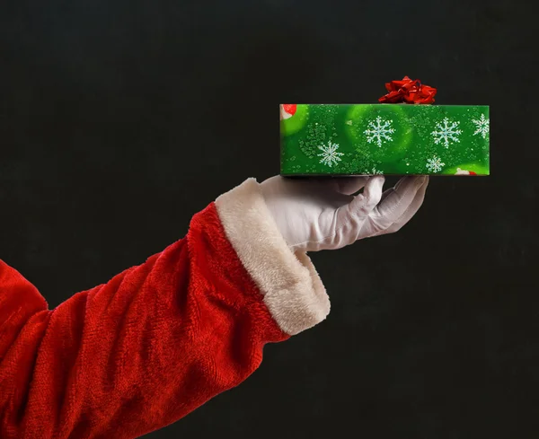 Santa Father Christmas hand with wrapping paper present and red star ribbon decoration on blackboard background — Stock Photo, Image