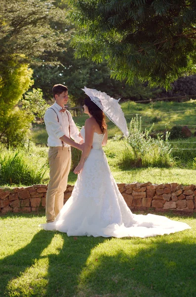 Bruid en bruidegom in tuin bruiloft met parasol — Stockfoto