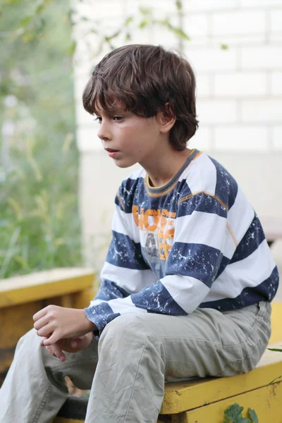 Sad boy sitting on a bench — Stock Photo, Image