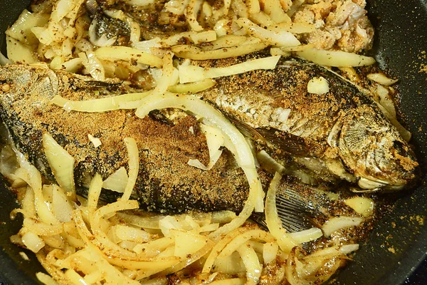 The fish is fried in a skillet with onions. — Stock Photo, Image