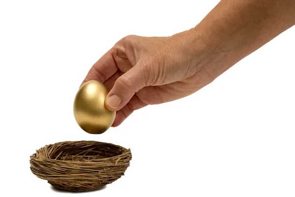 Colocando ovo dourado em ninho isolado em branco — Fotografia de Stock