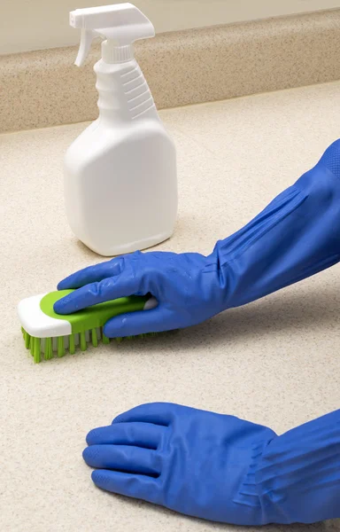 用蓝色橡胶手套的擦洗厨房柜台。 — 图库照片