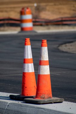 Yeni otopark inşaatında arka planda bir trafik namlusu olan trafik konilerinin dikey yakın çekimi. Fıçı bilerek odaklanamıyor..