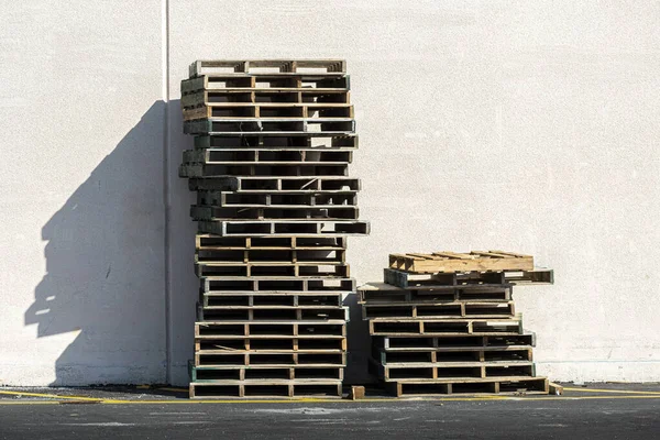 Boş ahşap palet yığınının yatay görüntüsü gölge ve kopyalama alanı olan bir duvara karşı..