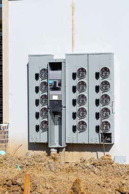 Çok ailelik yeni apartman inşaatı için elektrik sayacı kurulumunun dikey görüntüsü.