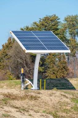 Elektrikli araç şarj istasyonuna bağlı bir güneş paneli dizisinin dikey görüntüsü.