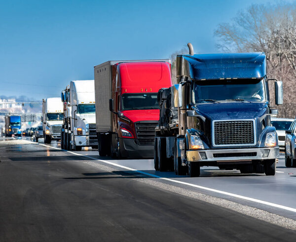 Horizontal shot of a steady stream of trucks rolling down the interstate highway.
