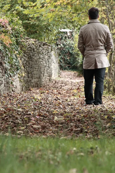 Homem andando sobre folhas caídas — Fotografia de Stock