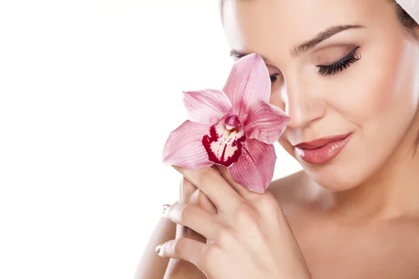 Bella donna con un asciugamano sulla testa in posa con orchidea — Foto Stock