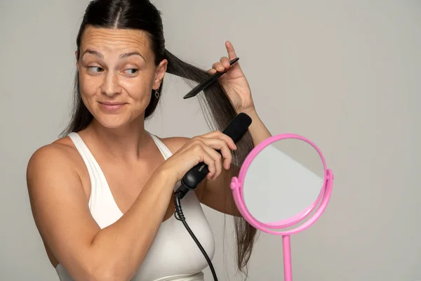 Jovem Mulher Sorridente Alisando Cabelo Com Alisador Fundo Cinza — Fotografia de Stock