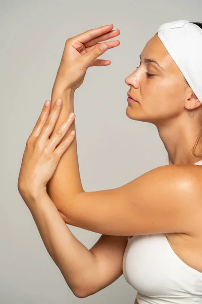 Ung Vacker Kvinna Tillämpar Kosmetisk Produkt Händerna Grå Bakgrund — Stockfoto