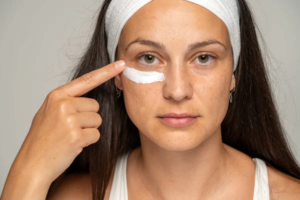 Portrait Young Woman Applying Cosmetic Product Her Eyes Gray Background — Stock Photo, Image