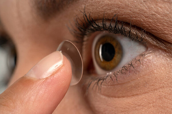 Close-up shot of young woman wearing contact lens. 