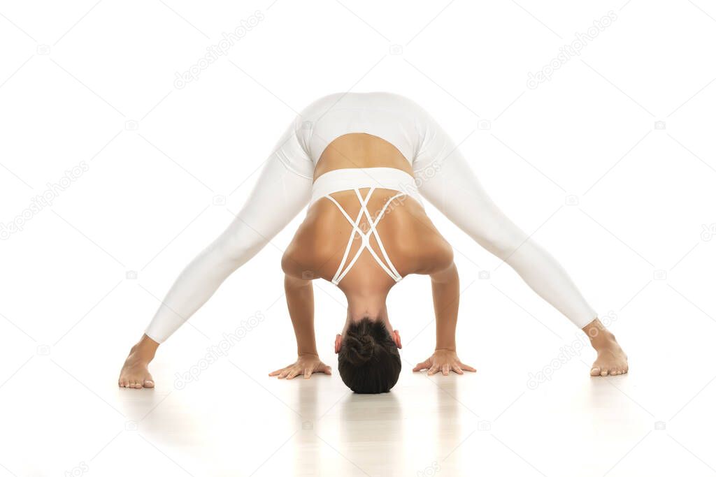 Yoga, sport, training and lifestyle concept - Young woman in white sportswear doing yoga practice. Prasarita Padottanasana