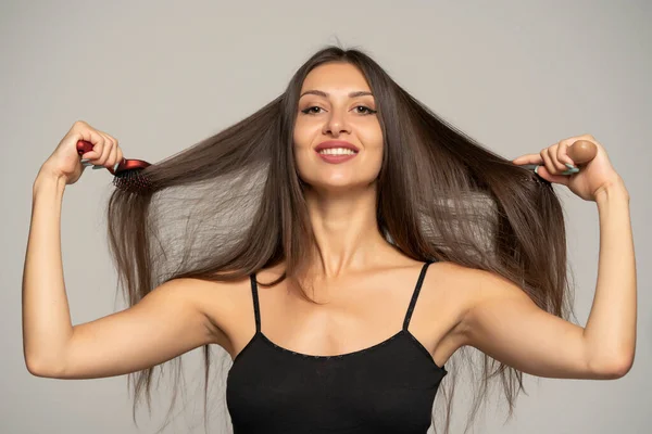Вид Спереду Щаслива Жінка Чистить Волосся Двома Пензлями Сірому Фоні — стокове фото