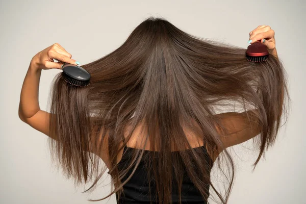 Вид Ззаду Жінки Чистить Волосся Двома Щітками Волосся Сірому Фоні — стокове фото