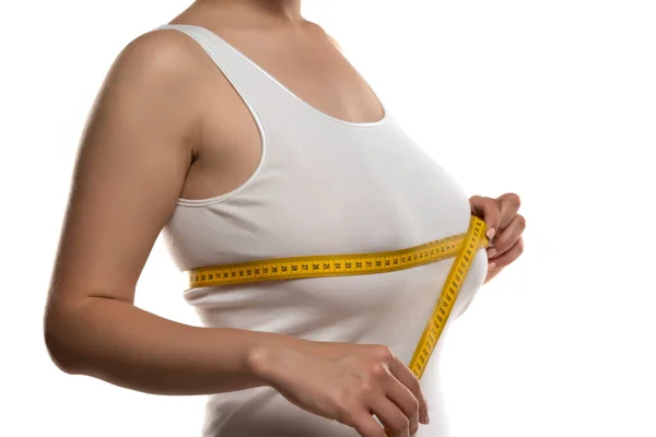 一个女人在白色的背景上用测量带测量她的大乳房 — 图库照片