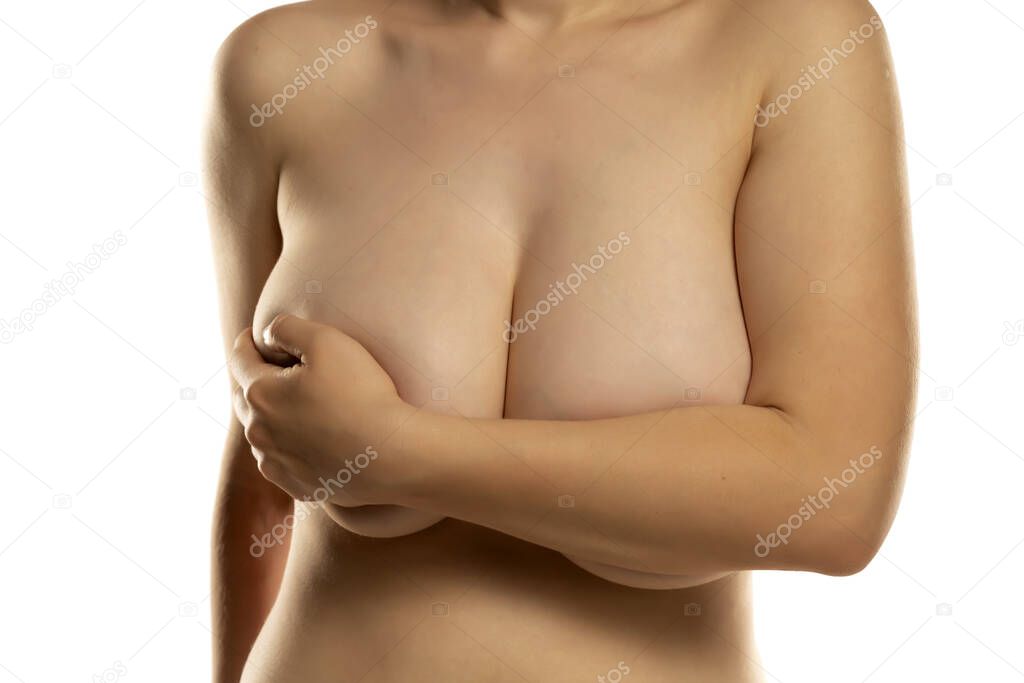 the woman covers with one hand her large breasts on a white background