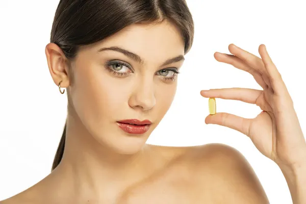 Vacker Ung Kvinna Som Håller Ett Vitaminpiller Fingrarna Vit Bakgrund — Stockfoto
