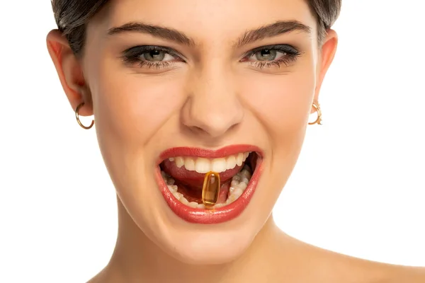 一个年轻 美丽的女人 有一颗白色背景的维生素丸在她的牙齿里 — 图库照片