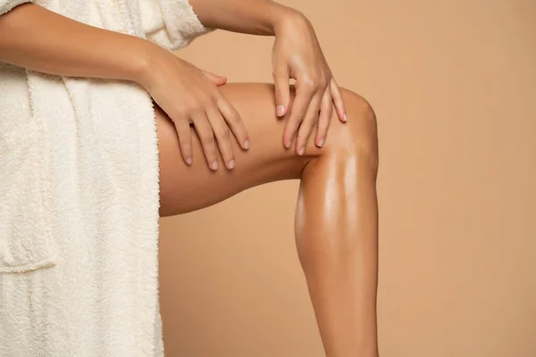 Close Een Vrouw Aanbrengen Crème Haar Benen Beige Achtergrond — Stockfoto
