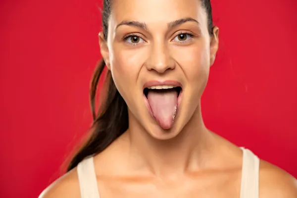 赤い背景に彼女の健康的な舌をアップ固執する女性 — ストック写真