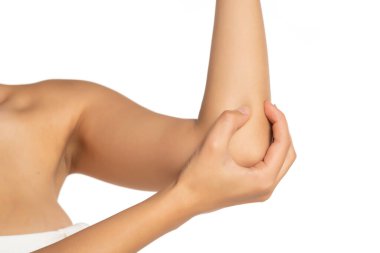 Kadın beyaz arka planda ağrıyan dirseğine masaj yapıyor.