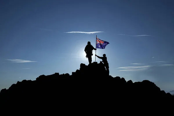 İki tanınmayan asker Avustralya bayrağını bir dağın tepesinde göndere çekiyor. 