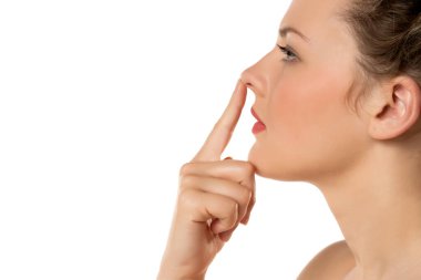 Beyaz arka planda burnuna dokunan sarışın ciddi bir kadının profili.