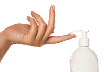 Bir kadın beyaz arka planda parmağında pompayla kozmetik bir ürün uygular.