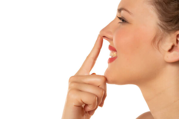 profile of a blonde smiling woman touching her nose on a white background